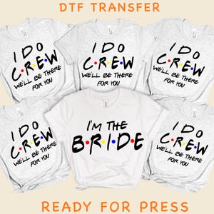 May include: A collection of six t-shirts featuring DTF transfers. Five heather gray shirts display the black text I DO CREW WE'LL BE THERE FOR YOU with colorful dots. One white shirt displays the black text I'M THE BRIDE with colorful dots.
