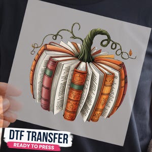 May include: A DTF transfer featuring a graphic of a pumpkin constructed from open books with orange, red, and brown spines, topped with a green vine stem. The text DTF TRANSFER READY TO PRESS is printed in black and pink at the bottom of the sheet.