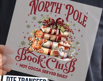 Könnte beinhalten: Ein quadratischer DTF-Transferbogen mit dem Text North Pole Book Club und Hot Cocoa Served Daily. Das Motiv zeigt einen Lebkuchenmann, einen Stapel Bücher mit roter Schleife, Stechpalmenbeeren und eine Tasse mit der Aufschrift Read.