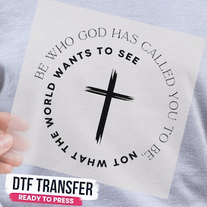 May include: A square DTF transfer sheet featuring a black cross in the center. The text "BE WHO GOD HAS CALLED YOU TO BE, NOT WHAT THE WORLD WANTS TO SEE" is printed in a circular black font around the cross on a clear, transparent background.