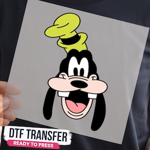 May include: A DTF transfer featuring a graphic of the cartoon character Goofy. The design shows the character's head with a tall yellow hat, black ears, a pink snout, and two prominent white teeth. The text DTF TRANSFER READY TO PRESS is visible.