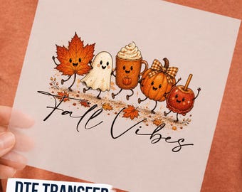 May include: A DTF transfer sheet featuring a cartoon illustration of a smiling maple leaf, ghost, coffee mug, pumpkin, and candy apple. The text Fall Vibes is written in black cursive script below the characters, surrounded by scattered autumn leaves.