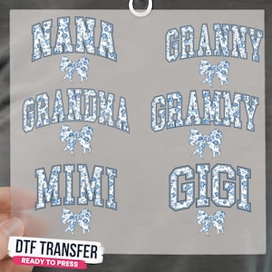 May include: A DTF transfer sheet featuring six arched words: NANA, GRANNY, GRANDMA, GRAMMY, MIMI, and GIGI. Each word is filled with a blue and white floral pattern and outlined in blue, accompanied by a matching floral bow graphic below each name.