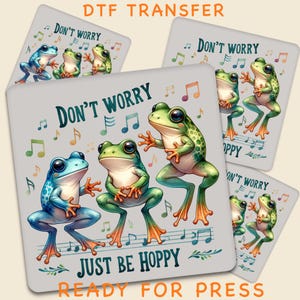 May include: Square DTF transfer featuring dancing frogs in blue and green with the text "DON'T WORRY JUST BE HOPPY". Musical notes and the phrase "READY FOR PRESS" are also included in the design.