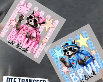 May include: Two DTF transfers featuring raccoons with heart-shaped sunglasses and backpacks. One raccoon wears a pink bow and bandana with pink stars and text reading BRUH we back. The other wears a blue cap and bandana with blue stars and text.