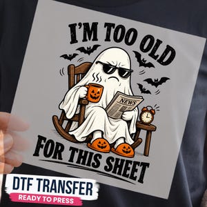 May include: A DTF transfer featuring a white ghost wearing sunglasses, sitting in a wooden rocking chair, holding an orange jack-o'-lantern mug and a newspaper. Text reads I'M TOO OLD FOR THIS SHEET. Includes bats, an alarm clock, and slippers.