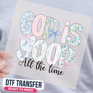 May include: A DTF transfer sheet featuring the text "GOD IS GOOD" in large, blocky letters filled with various pastel floral, gingham, and striped patterns, accented by small light blue and pink bows, with "All the time" in black script below.