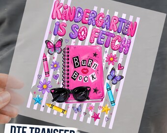 May include: A DTF transfer sheet featuring the text Kindergarten Is So Fetch in pink and purple leopard print. The design includes a pink spiral-bound Burn Book, black sunglasses, butterflies, crayons, stars, and flowers on a striped background.