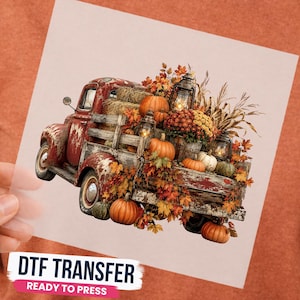 May include: A DTF transfer featuring a weathered red pickup truck loaded with autumn harvest elements including orange pumpkins, hay bales, dried corn stalks, colorful fall foliage, and vintage-style lanterns. The design is printed on a clear sheet.