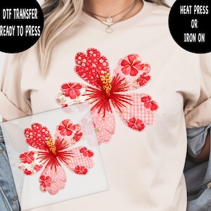 May include: A DTF (Direct to Film) transfer featuring a large, stylized red hibiscus flower design. The flower has multiple petal patterns, including polka dots and gingham. The text "DTF TRANSFER READY TO PRESS" is visible.