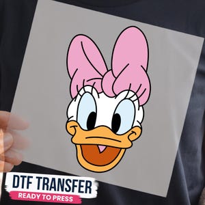 May include: A DTF transfer featuring a graphic of Daisy Duck's face with a large pink bow, white feathers, and an orange beak. The design is printed on a clear sheet with the text DTF TRANSFER READY TO PRESS printed in black and pink at the bottom.