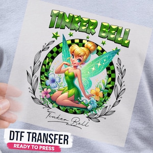 May include: A DTF transfer sheet featuring a graphic of Tinker Bell with blonde hair in a bun, wearing a green dress and translucent wings. The design includes a green checkered circle, floral accents, and the text TINKER BELL in green.