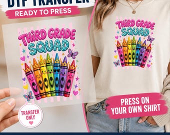 May include: A DTF transfer sheet and a cream-colored t-shirt featuring a graphic print of six colorful cartoon crayons with faces and crowns. The text reads "THIRD GRADE SQUAD" in pink and blue. The design includes small hearts, stars, and butterflies.