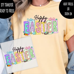 Peut inclure: Un t-shirt jaune clair avec un motif coloré "Joyeuses Pâques". Le design présente des lettres aux couleurs pastel, des œufs de Pâques, des carottes et des papillons. L'image montre également un transfert DTF prêt à presser.