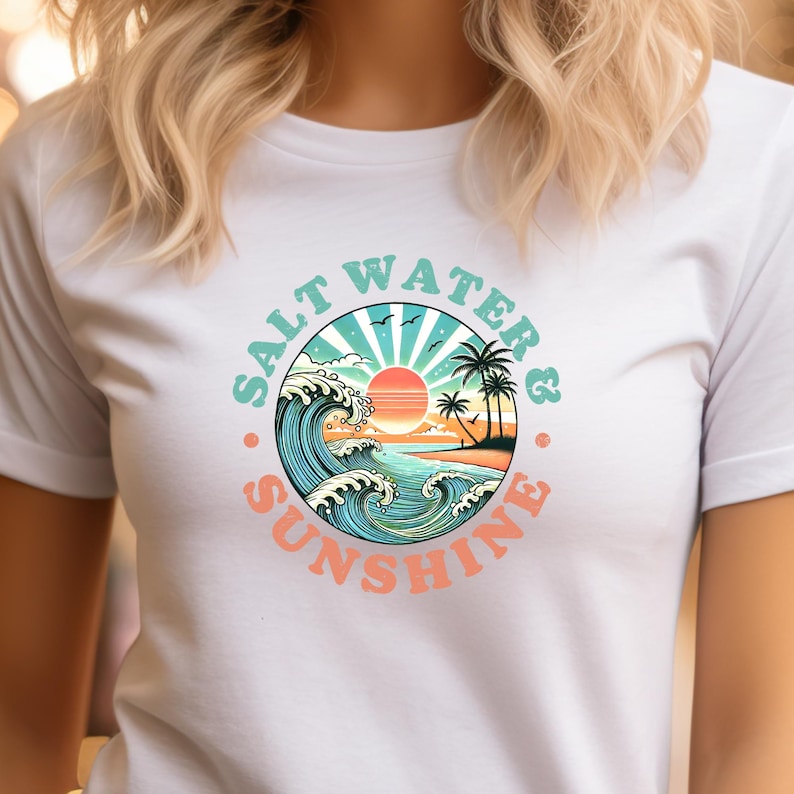 May include: White t-shirt with a graphic of a sunset over the ocean with waves and palm trees. The graphic is in a circle with the text "Salt Water & Sunshine" around it.