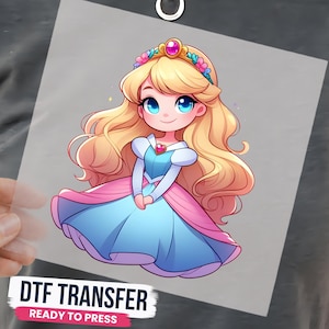 May include: A DTF transfer featuring a cartoon princess with long blonde hair, blue eyes, and a tiara. She wears a blue and pink dress with a heart-shaped pendant. The text reads DTF TRANSFER READY TO PRESS in black and pink on a white background.
