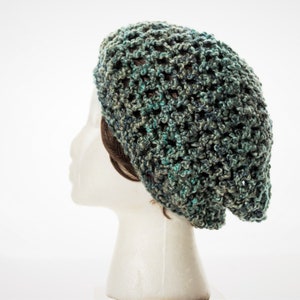 May include: A green and blue crocheted beanie hat with a loose, open weave.