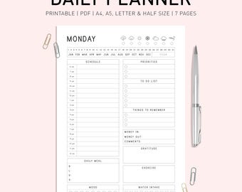 Puede incluir: Un planificador diario imprimible en blanco y negro con la palabra "MONDAY" en la parte superior. El planificador incluye secciones para el horario, las prioridades, la lista de tareas, las cosas que hay que recordar, el dinero que entra, el dinero que sale, los comentarios, la gratitud, la comida diaria, el ejercicio, el estado de ánimo y la ingesta de agua.