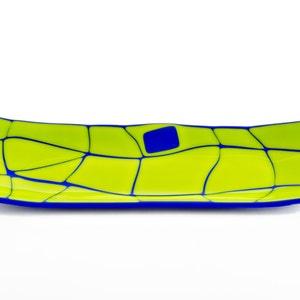 May include: A rectangular glass tray in lime green, with a mosaic pattern of blue lines and a single blue square. The edges are outlined in blue. The tray is approximately 30 cm long.