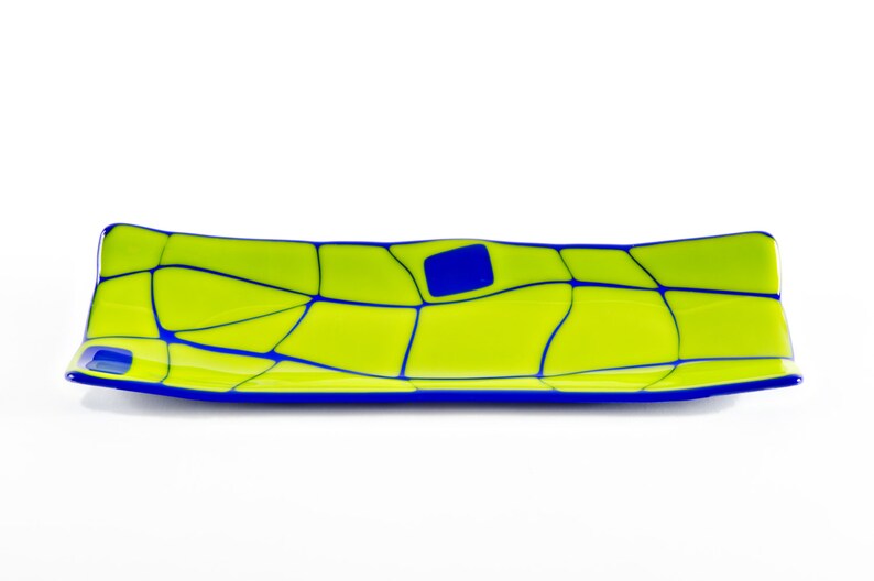 May include: A rectangular glass tray in lime green, with a mosaic pattern of blue lines and a single blue square. The edges are outlined in blue. The tray is approximately 30 cm long.