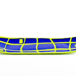 May include: A long, rectangular serving dish with a bold design. The dish has a blue interior with a grid pattern in bright yellow. The rim is also yellow, creating a striking contrast. The dish is ideal for serving snacks or small dishes.