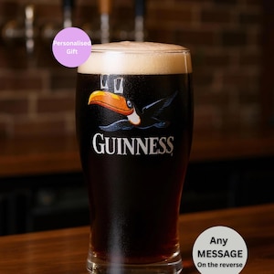 May include: A pint glass of Guinness stout with a creamy head, featuring the Guinness logo and a toucan graphic. The text "Personalised Gift" and "Any Message On the reverse" are also visible on the image.