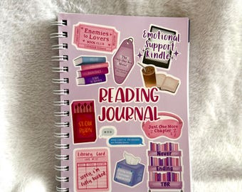 May include: A light purple spiral-bound reading journal featuring various book-themed stickers, including a Kindle, a stack of books, a library card, and text that reads Reading Journal, Emotional Support Kindle, and sorry, i can't i'm the enemies.