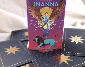 May include: A tarot card with a purple background and gold accents. The card features a woman with wings and a lion. The text on the card reads "Star of Inanna".
