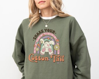 Könnte beinhalten: Ein grünes Sweatshirt mit einem Aufdruck eines Kaninchens mit einem Regenbogen und dem Text "Shake Your Cotton Tail".