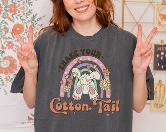 Könnte beinhalten: Ein dunkelgraues T-Shirt mit einem Regenbogen und einem Comic-Kaninchen. Der Text "Shake Your Cotton Tail" ist auf dem Shirt aufgedruckt.