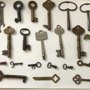 May include: A collection of vintage keys, including skeleton keys, ornate keys, and keys with numbers. The keys are made of brass and steel and have a variety of finishes, including polished, antique, and tarnished.
