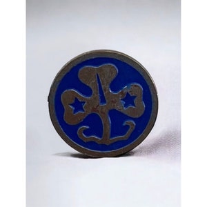 May include: A blue and silver Girl Scout pin with a four-leaf clover design and two stars.