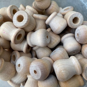 May include: A collection of unfinished wooden knobs, each with a rounded top and a cylindrical base. The knobs are light brown in color and appear to be made of natural wood. They are likely intended for use in furniture or craft projects.