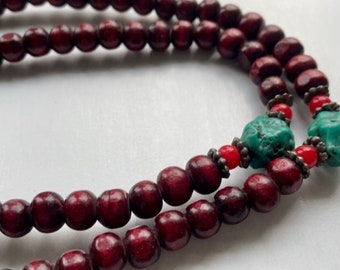 Long turquoise and wood vintage beaded necklace on red satin