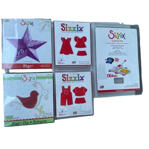 May include: A set of four Sizzix Bigz die cutting templates for crafting. The dies feature a star, a bird, a dress, and overalls. The dies are made by Ellison and are compatible with Sizzix Big Shot and Big Kick machines. The packaging includes the text "Sizzix The Little Die Cutter That Makes a Big Difference".