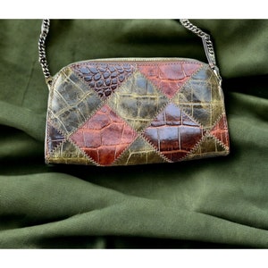 May include: A small, brown and green patchwork leather handbag with a chain strap. The bag has a diamond pattern and is made of crocodile-embossed leather.