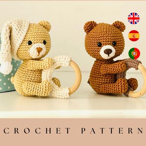 May include: Two crocheted teddy bear toys. One is light yellow with a white hat and the other is brown. Both bears hold a wooden ring. The text "CROCHET PATTERN" is at the bottom of the image.