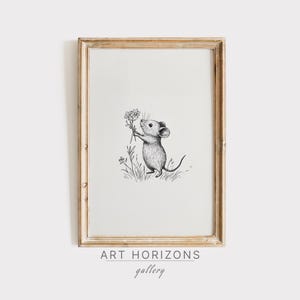 Puede incluir: Una impresión artística enmarcada con un dibujo a lápiz de un ratón sosteniendo flores. La obra de arte en blanco y negro está sobre un fondo crema, dentro de un marco de madera marrón claro. El texto "ART HORIZONS gallery" está en la parte inferior.