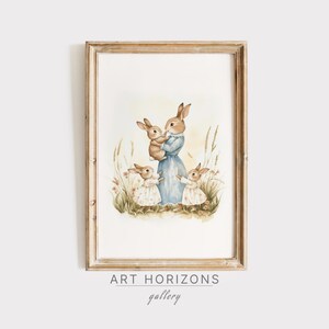 May include: Watercolor print of a mother rabbit in a blue dress holding a baby rabbit, surrounded by three other rabbits in a field. The artwork is framed in a light brown wooden frame. The text "ART HORIZONS gallery" is at the bottom.