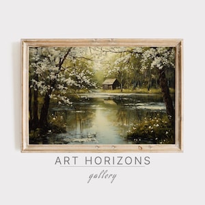 May include: A framed painting of a landscape with a small cabin on a lake surrounded by trees. The trees are in bloom with white flowers. The lake is reflecting the sky and trees. The painting is in a light wood frame.