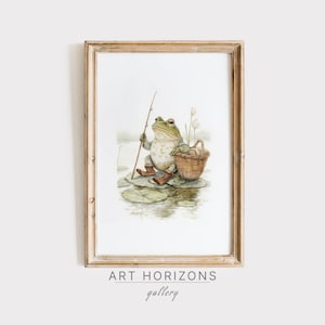 May include: A framed watercolor print featuring a frog dressed in boots, holding a fishing rod, and sitting on a lily pad. A woven basket sits beside the frog. The print is in a wooden frame. The text "ART HORIZONS gallery" is at the bottom.