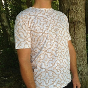 Op de afbeelding: Wit T-shirt met een bruin geometrisch patroon.