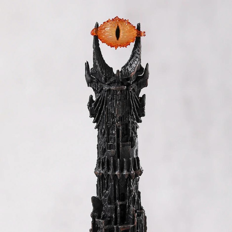 May include: A black tower with an orange eye at the top. The tower has a detailed, textured surface. The eye is orange with a black pupil. The overall design is reminiscent of a fantasy theme.