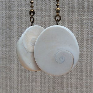 May include: Two white seashell fan pull chains with a brass chain attached to each.