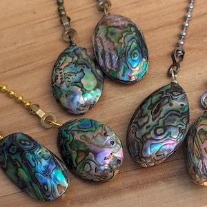 May include: Five iridescent abalone shell fan pull chains with gold and silver chains. The shells are oval shaped and have a variety of colors, including green, blue, purple, and gold.