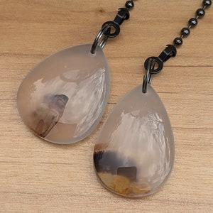 May include: Two agate stone pull chains with black metal chains and clips. The stones are translucent with brown and white patterns.