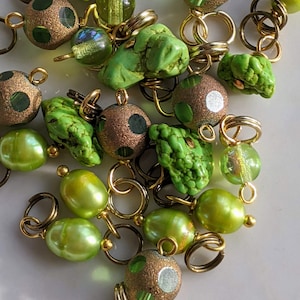May include: A collection of green and gold beads and charms, including turquoise, pearl, and glass beads. The beads are strung on gold jump rings and are perfect for jewelry making.