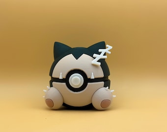 May include: A black, green, and beige toy figure of a Pokemon character. The figure has a round body with a black and white Pokeball design. The figure has a white Z on its head and two small beige ears.