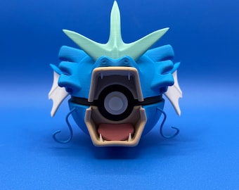 May include: A blue and green 3D printed Pokemon figure of Blastoise, a water-type Pokemon. The figure is in a closed mouth position with a Pokeball inside.