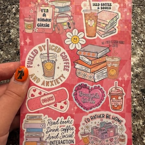 May include: A set of stickers featuring illustrations of books, coffee, and hearts. The stickers have text that says "I'm a kindle girlie", "Fueled by iced coffee and anxiety", "Bookish Girlie", "Read books, drink coffee, avoid social interaction", "I'd rather be home finishing my TBR pile", "All I need is good books & coffee", "Iced coffee & books", and "Reading fuel".